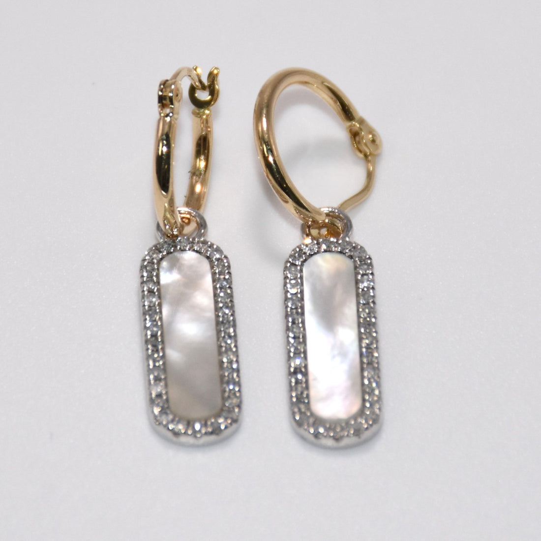 Pair of gold hoop earrings with rectangular gemstones on a light gray background