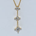 Gold necklace with three diamond pendants on a light gray background