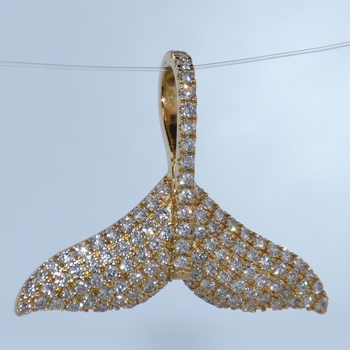Gold and diamond pendant on a light blue background