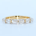 Gold ring with emerald-cut diamonds on a light blue background