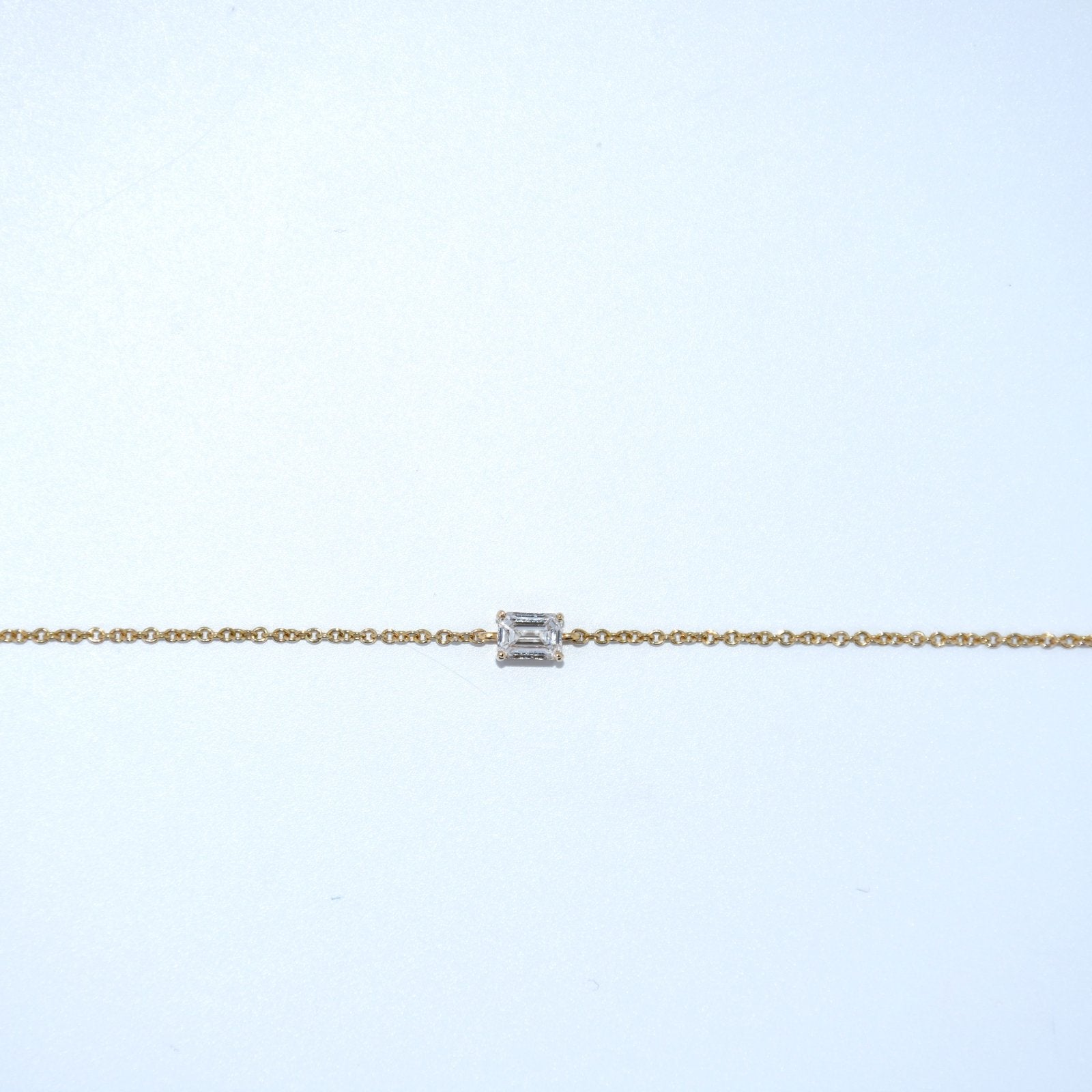Gold bracelet with a diamond on a light gray background