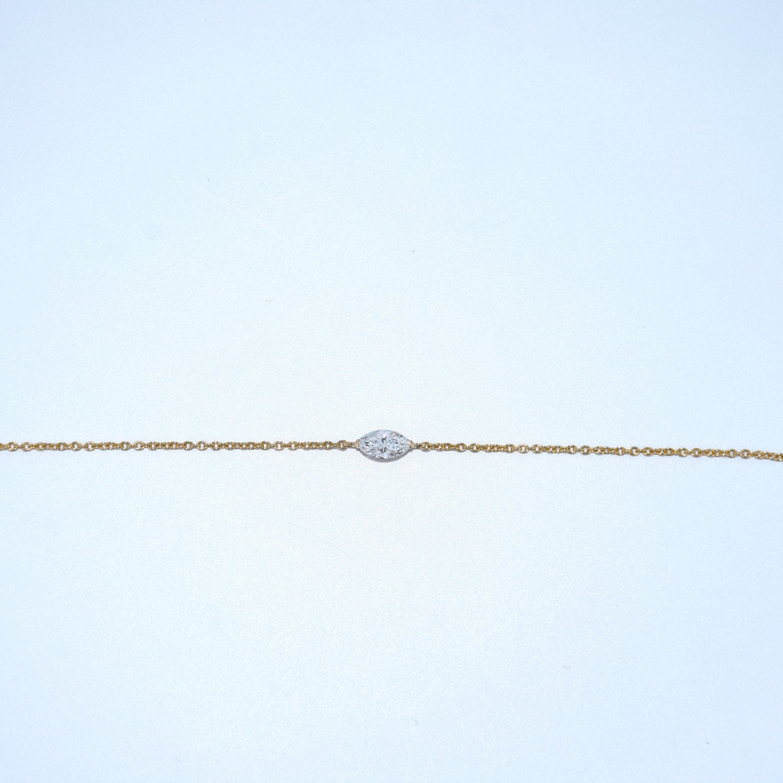 Gold bracelet with a diamond clasp on a light blue background