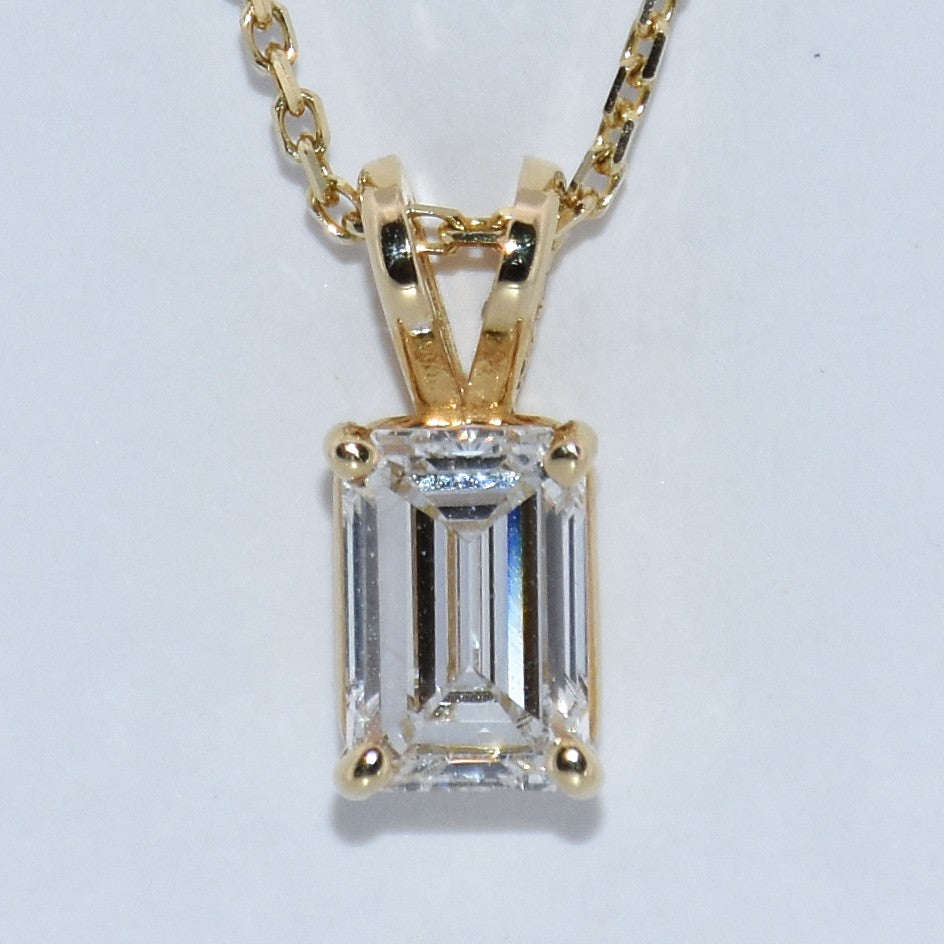 Gold pendant with a rectangular gemstone on a white background