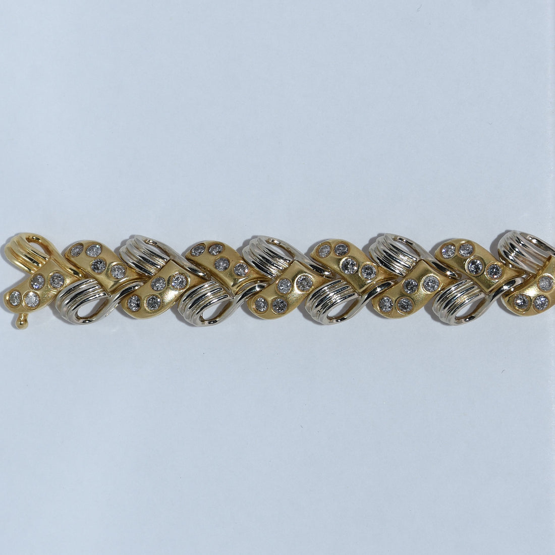 Gold and silver bracelet with rhinestones on a light gray background