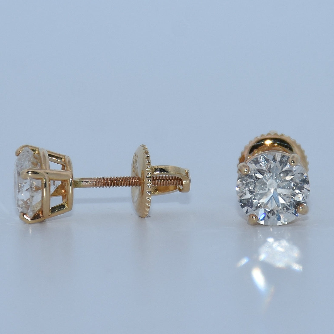 Pair of rose gold diamond earrings on a light gray background