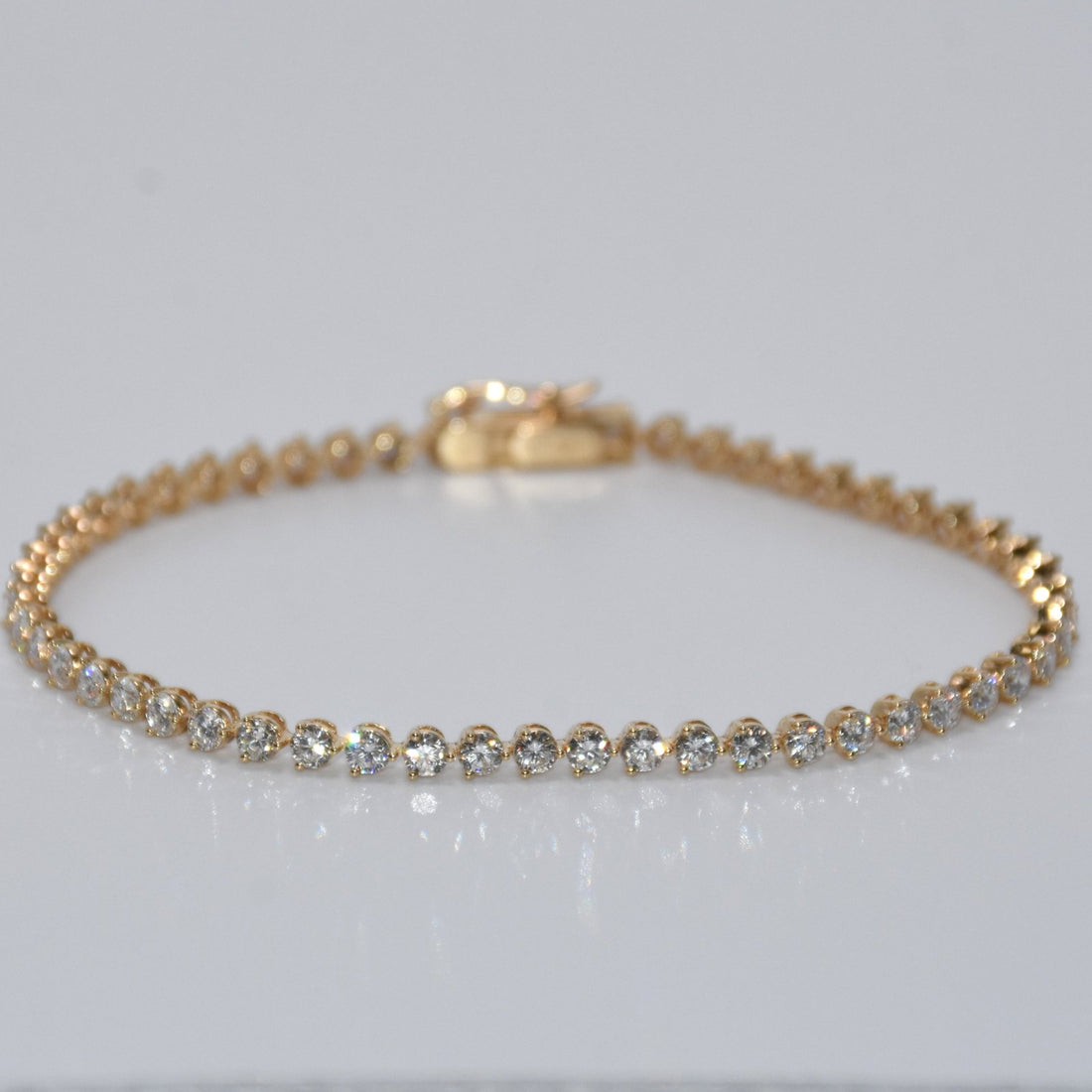 Gold bracelet with clear stones on a light gray background