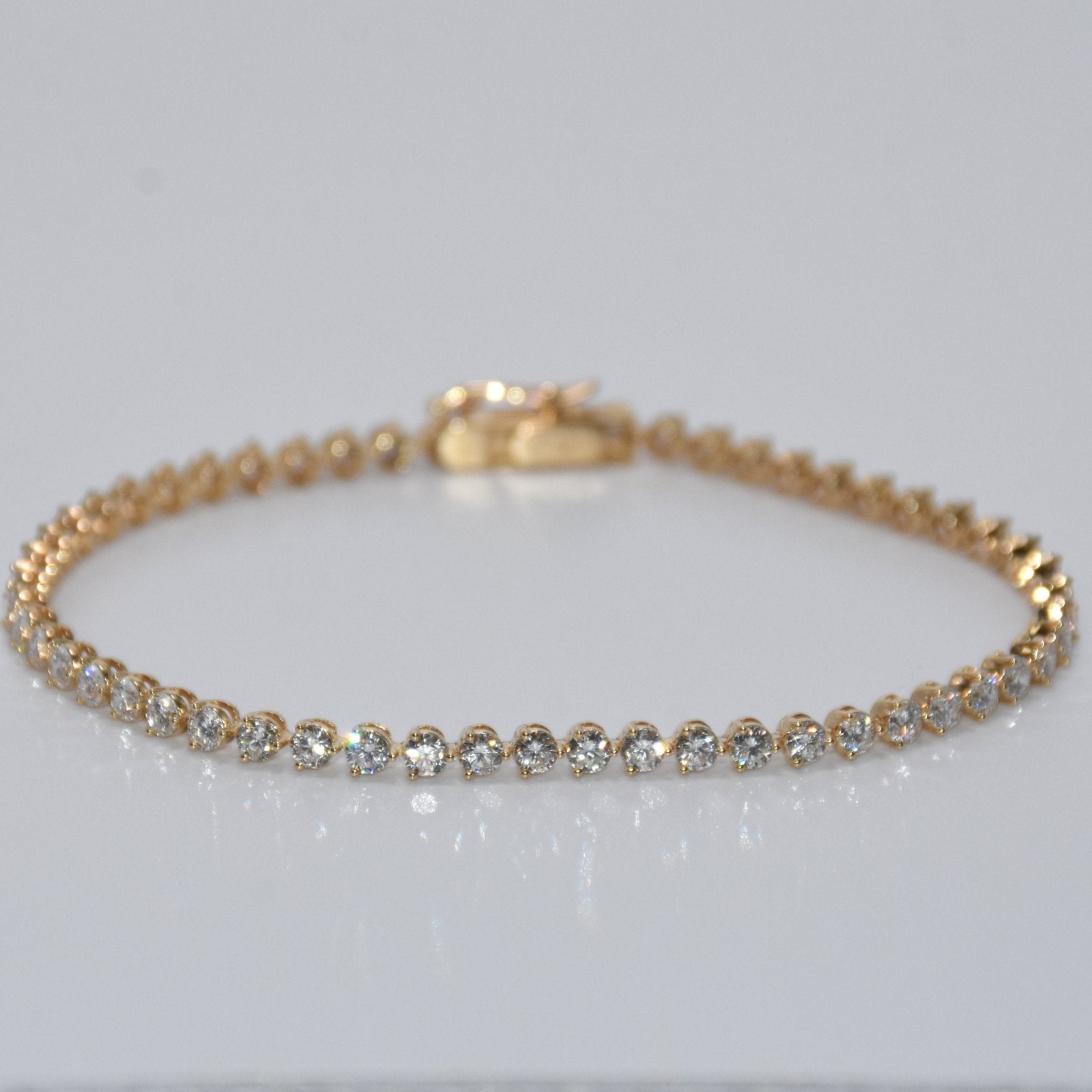 Gold bracelet with clear stones on a light gray background