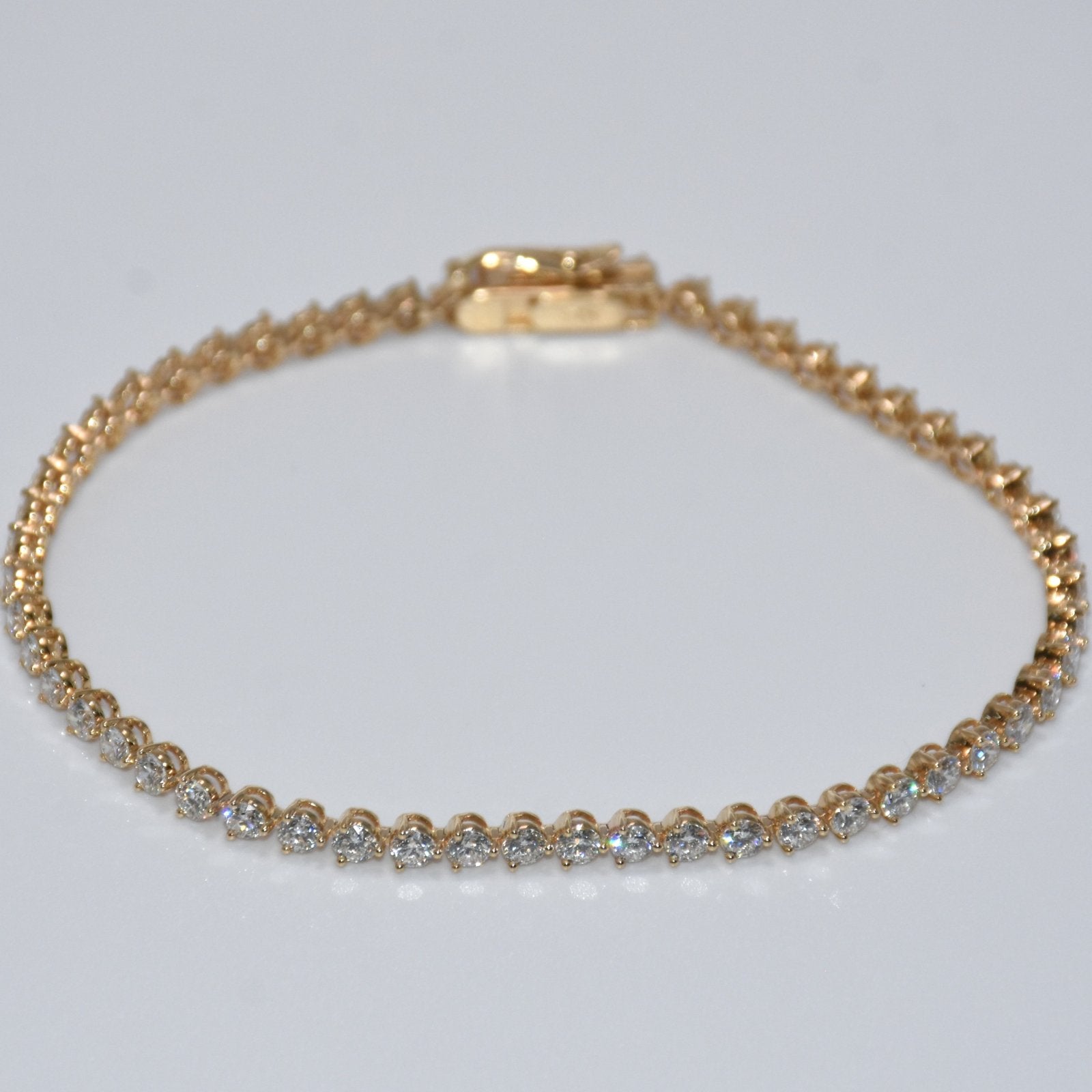 Gold bracelet with clear stones on a light gray background