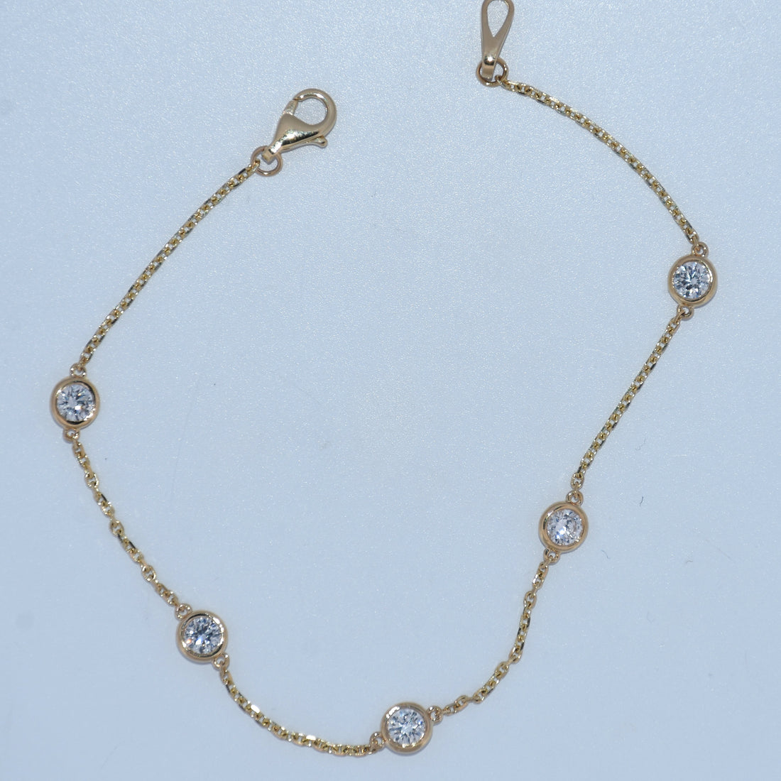 Gold bracelet with diamond accents on a light blue background