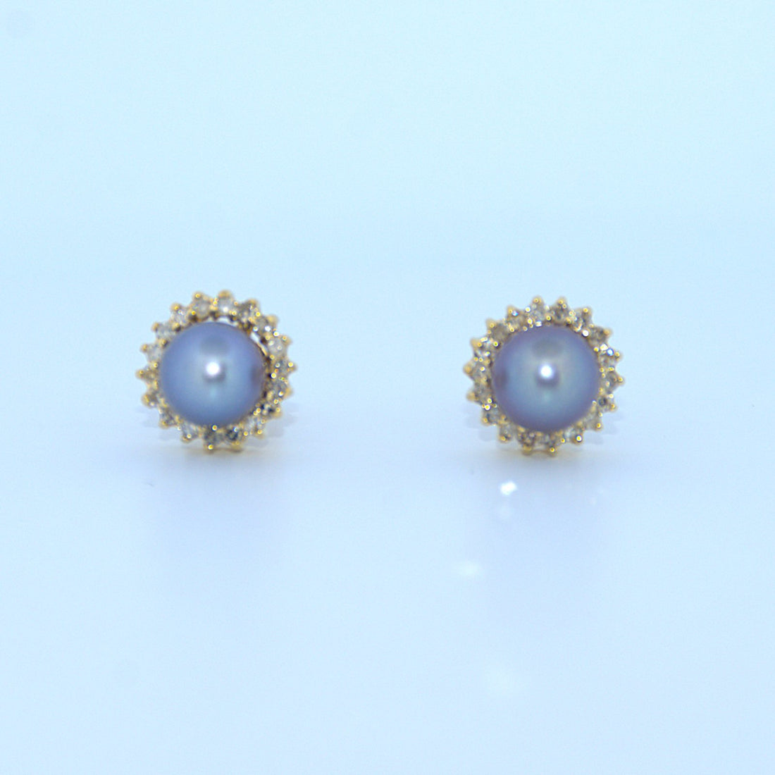 Pair of pearl earrings with gold accents on a light blue background