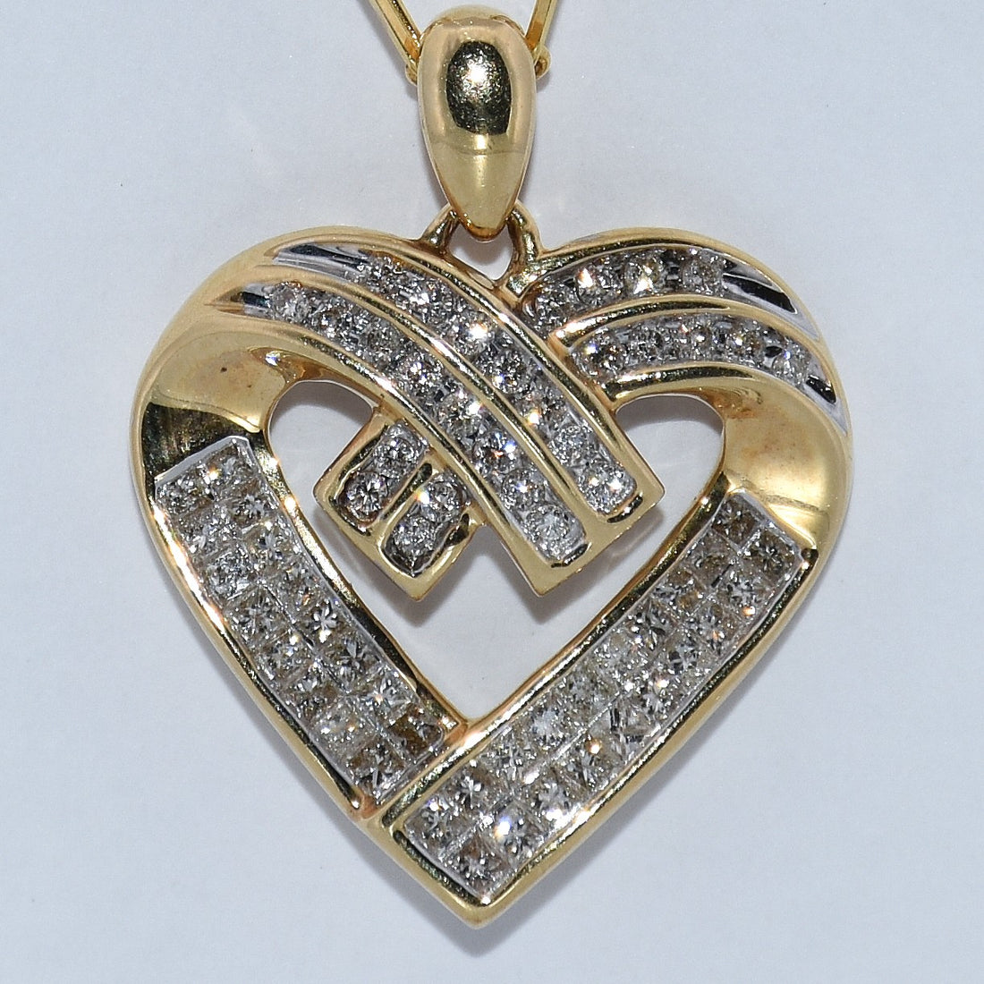 Gold heart-shaped pendant with diamond accents on a light gray background