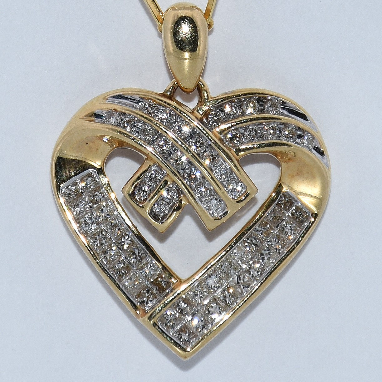 Gold heart-shaped pendant with diamond accents on a light gray background