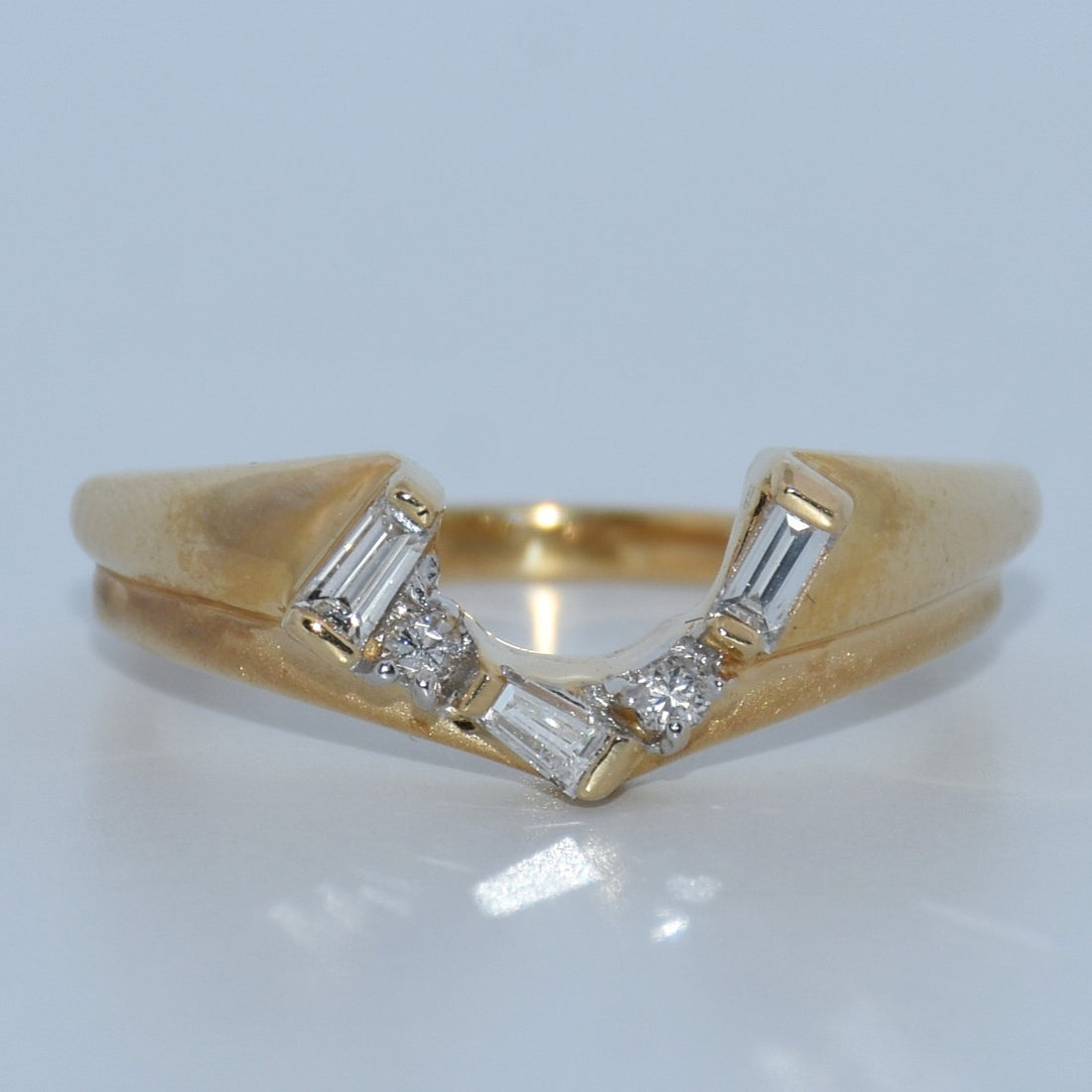 Gold ring with diamond accents on a reflective surface