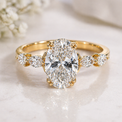 Gold ring with a large diamond and smaller diamonds on the sides, on a soft white background.