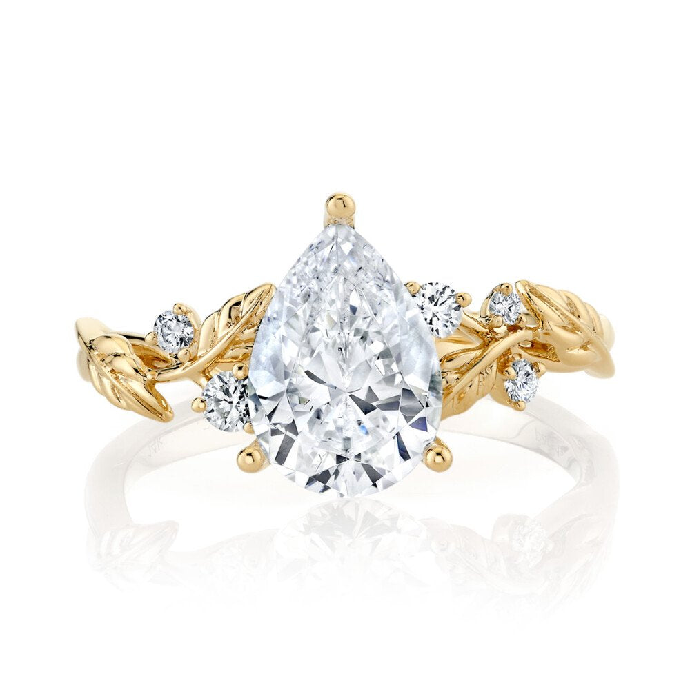 Gold ring with a pear-shaped diamond on a white background