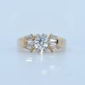 Gold ring with a central diamond and baguette-cut stones on a light blue background