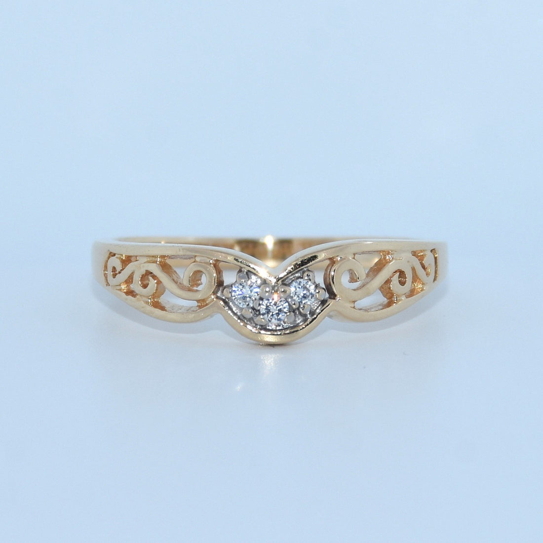 Gold ring with diamond design on a light blue background