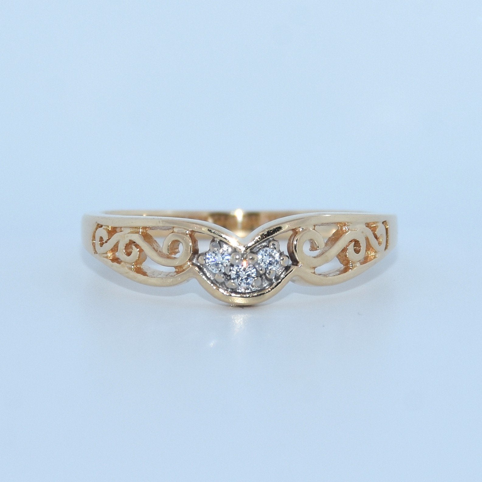 Gold ring with diamond design on a light blue background
