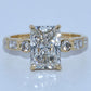 Gold ring with a large diamond and smaller diamonds on a light gray background