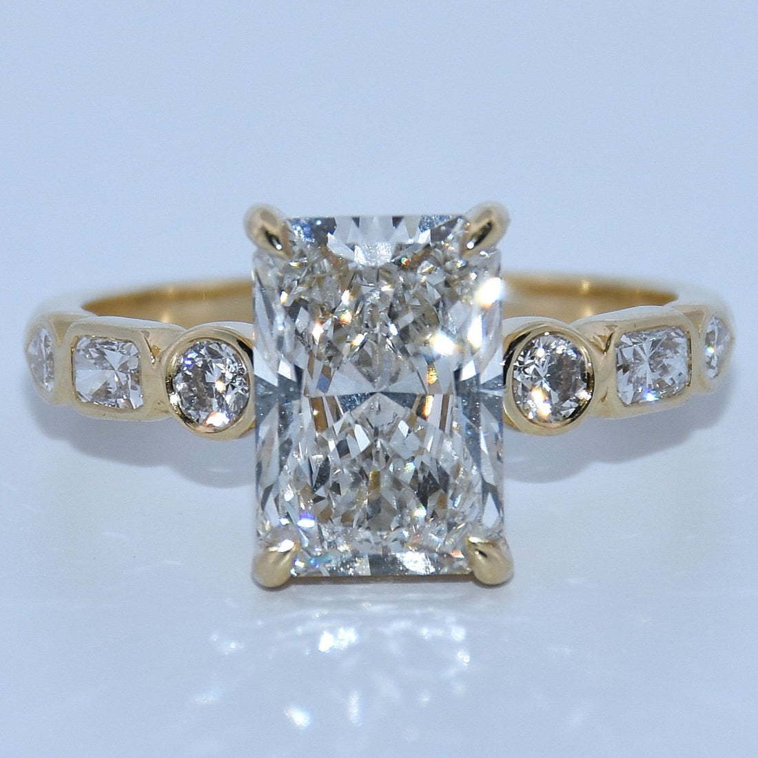 Gold ring with a large diamond and smaller diamonds on a light gray background
