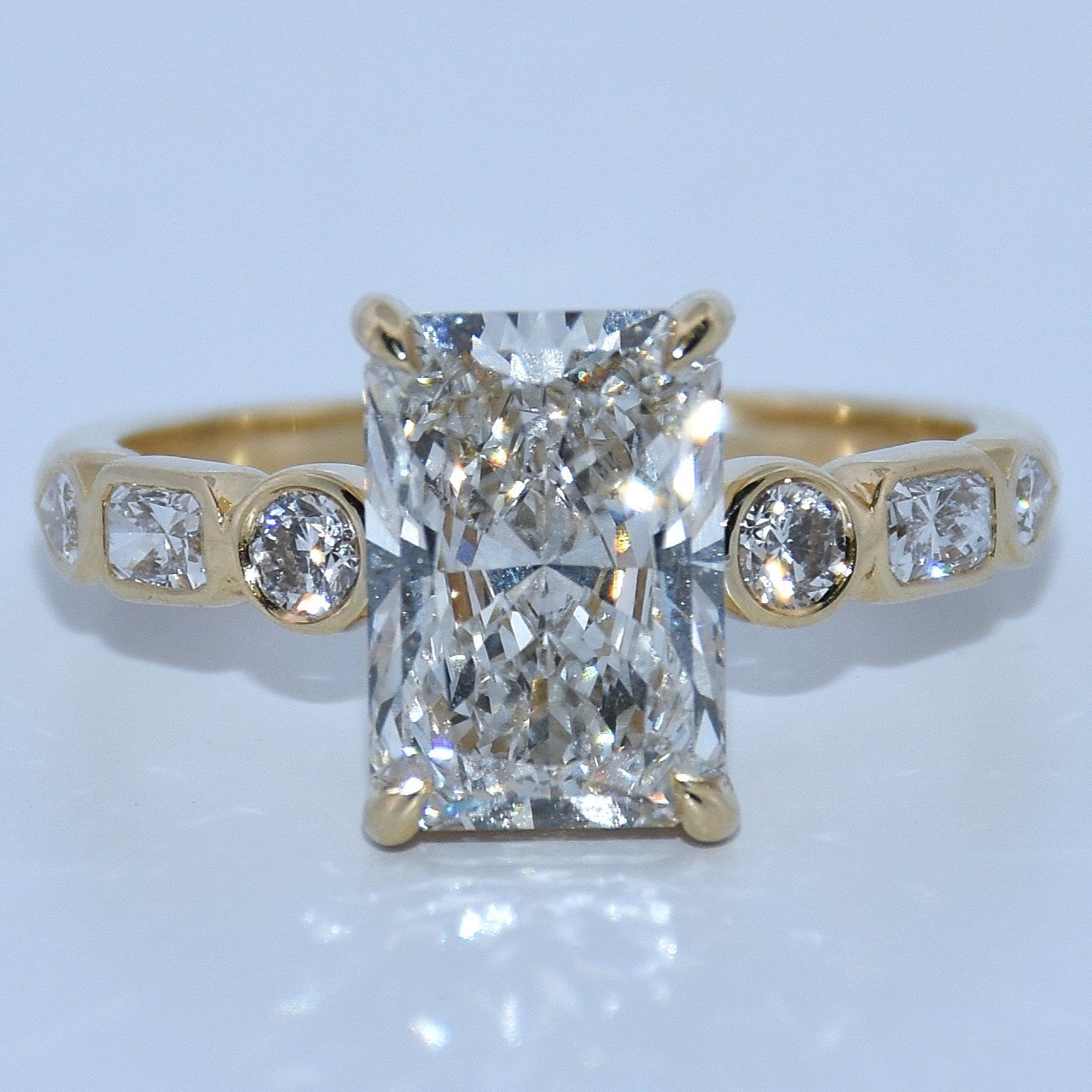 Gold ring with a large diamond and smaller diamonds on a light gray background