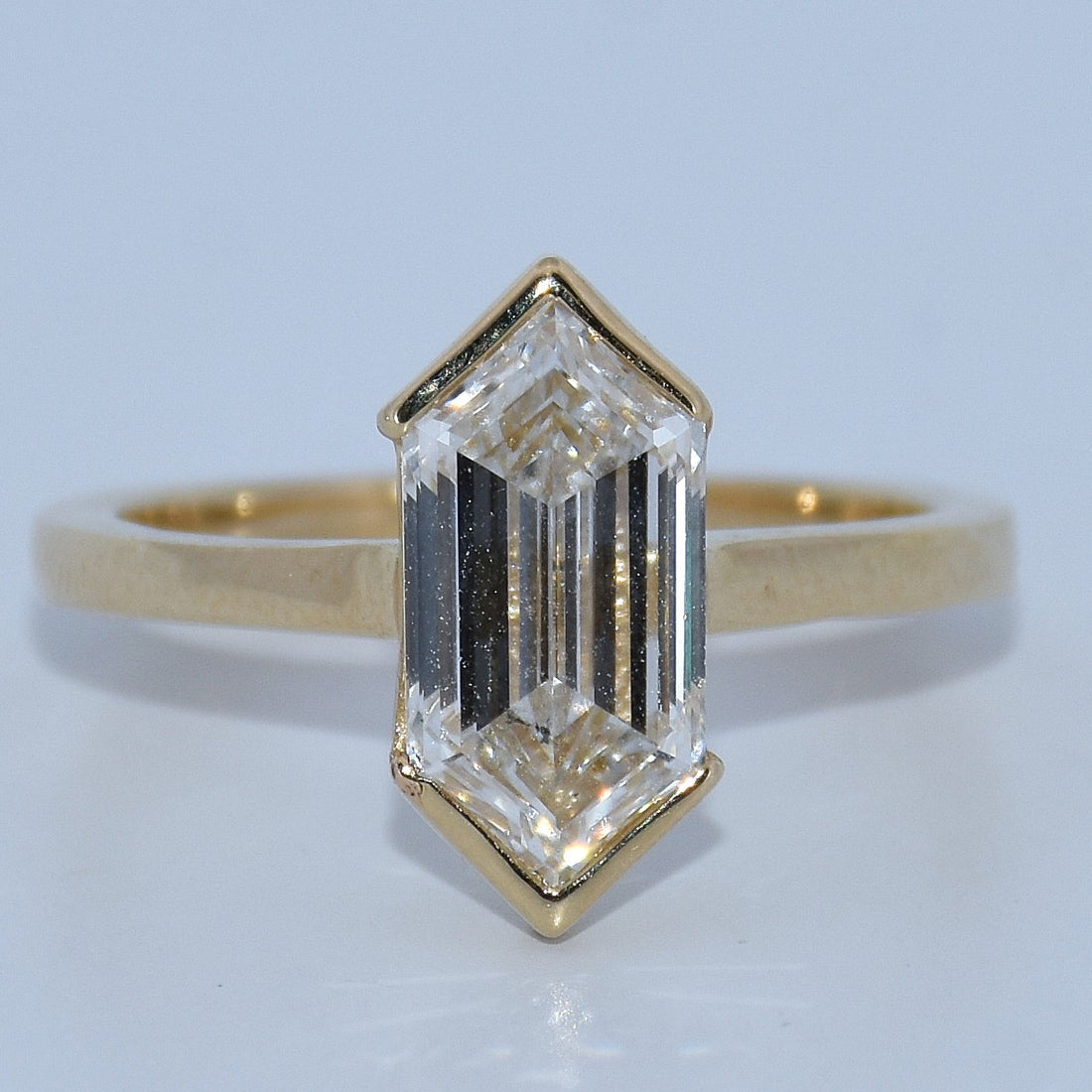 Gold ring with a large rectangular diamond on a light blue background