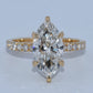 Gold ring with a large marquise-shaped diamond and smaller diamonds on a light gray background