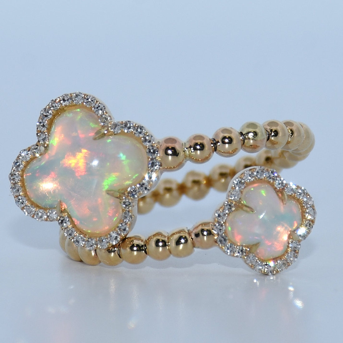 Gold bracelet with opal flower charms on a light blue background