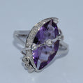 Silver ring with a large purple gemstone on a light gray background