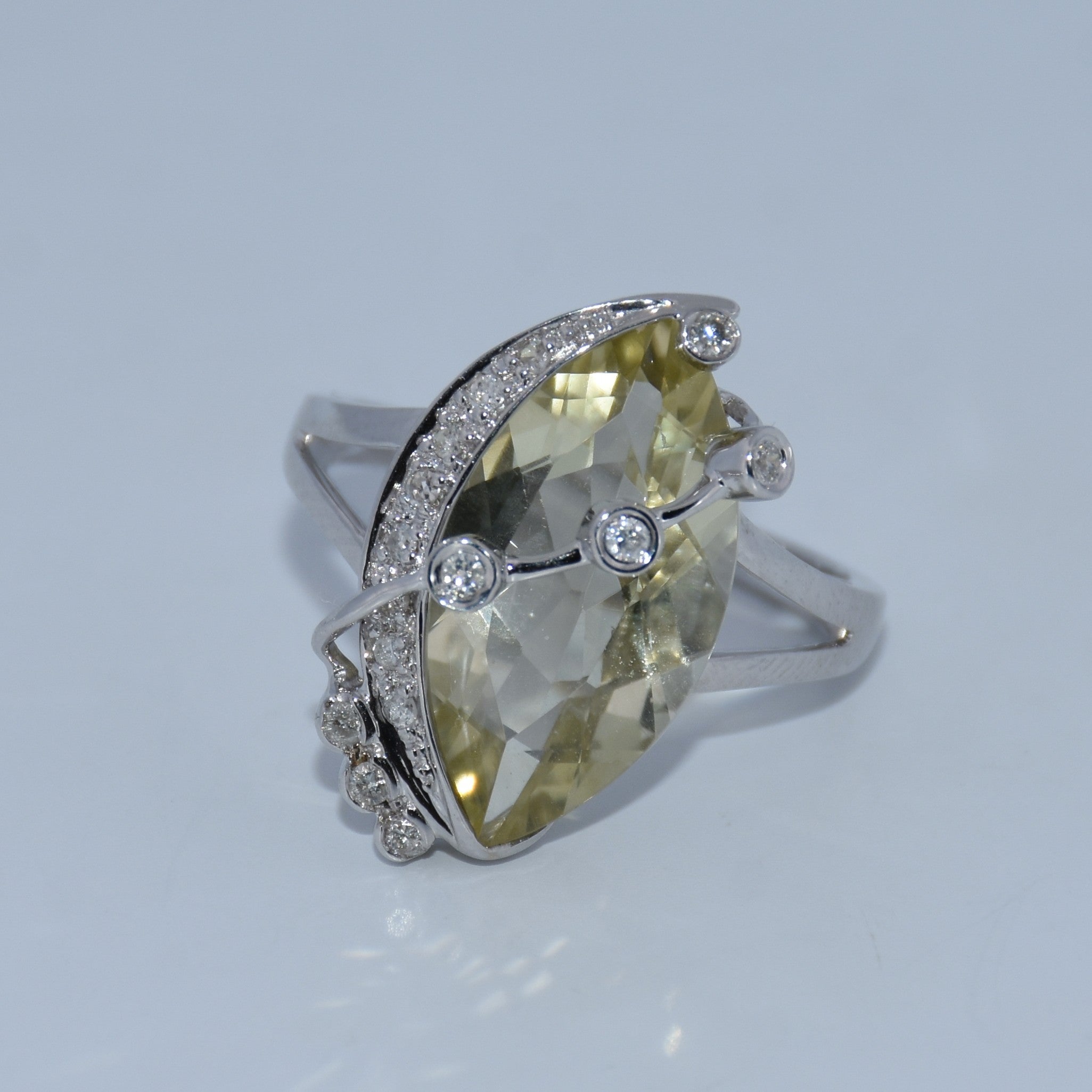 Ring with a large yellow gemstone and smaller diamonds on a light gray background