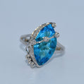 Ring with a blue gemstone and silver accents on a light gray background