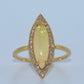 Gold ring with a large central gemstone and smaller stones on a light blue background