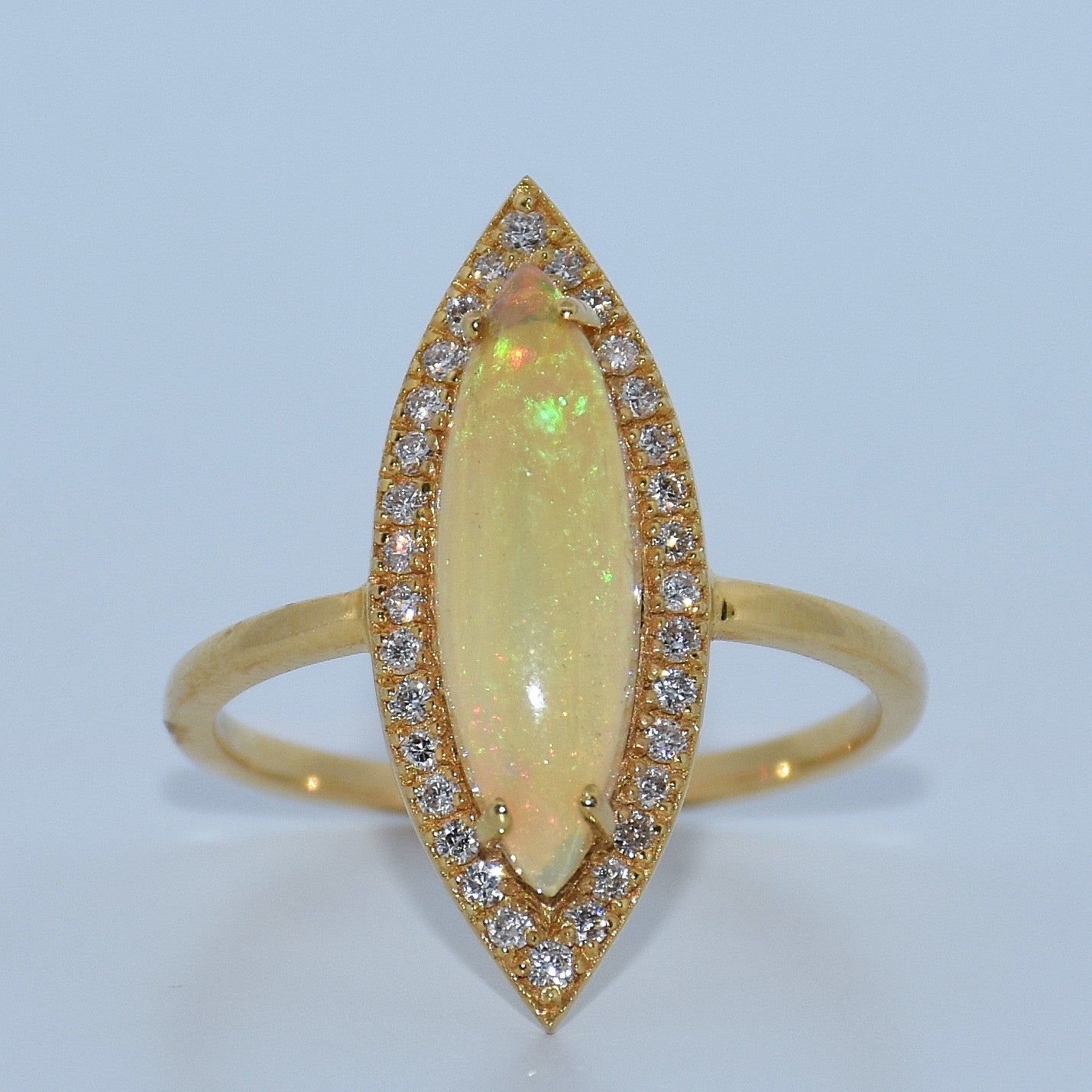 Gold ring with a large central gemstone and smaller stones on a light blue background