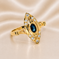 Gold ring with blue gemstone and diamond accents on a beige fabric background 19.2K Portuguese Gold | .35ct Natural Oval Blue Sapphire .15ct Natural Diamond Ring