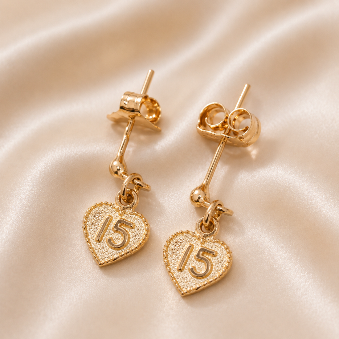 Gold heart-shaped earrings with number '15' on a beige fabric background 19.2K Portuguese Gold | 15th Earrings – Elegant Quinceañera Gold Jewelry