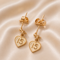 Gold heart-shaped earrings with number '15' on a beige fabric background 19.2K Portuguese Gold | 15th Earrings – Elegant Quinceañera Gold Jewelry