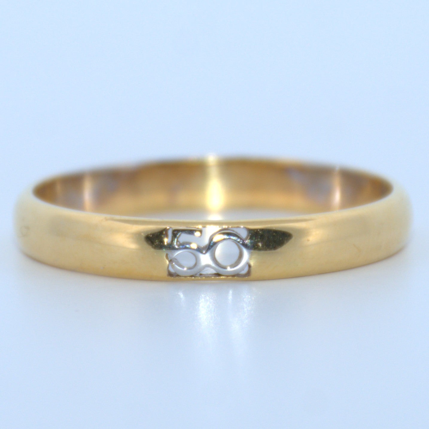 Gold ring with a small design on a light gray background