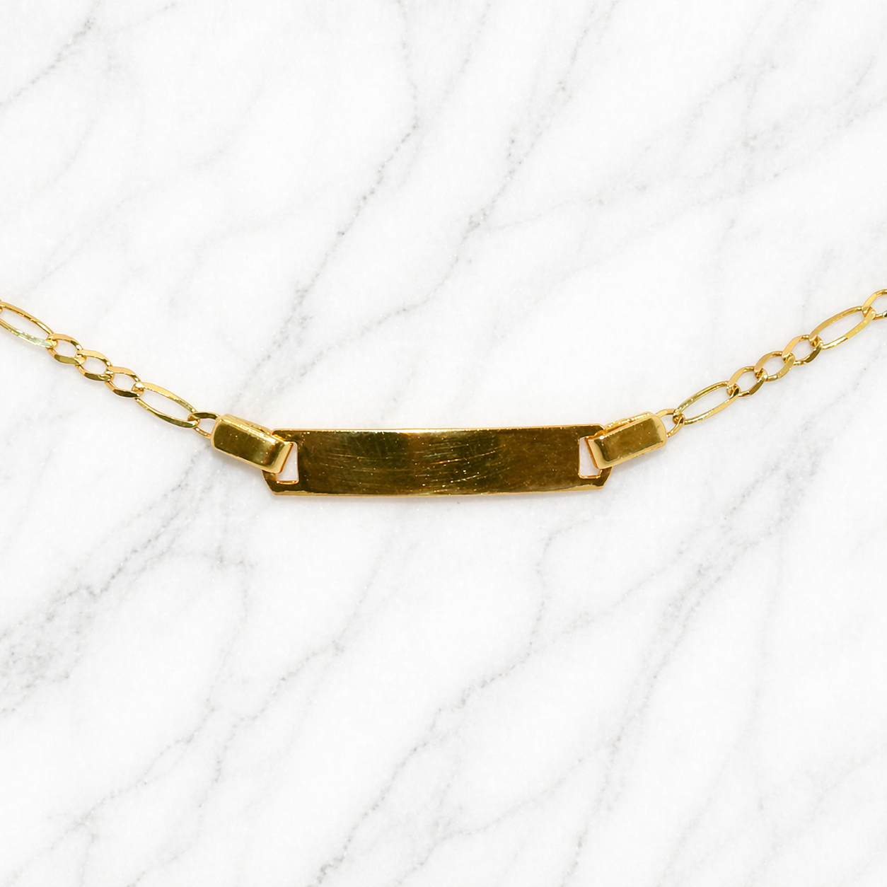 19.2K Portuguese Gold | 6" Kids Figaro ID Bracelet with Adjustable Links Gold necklace with a bar pendant on a white background