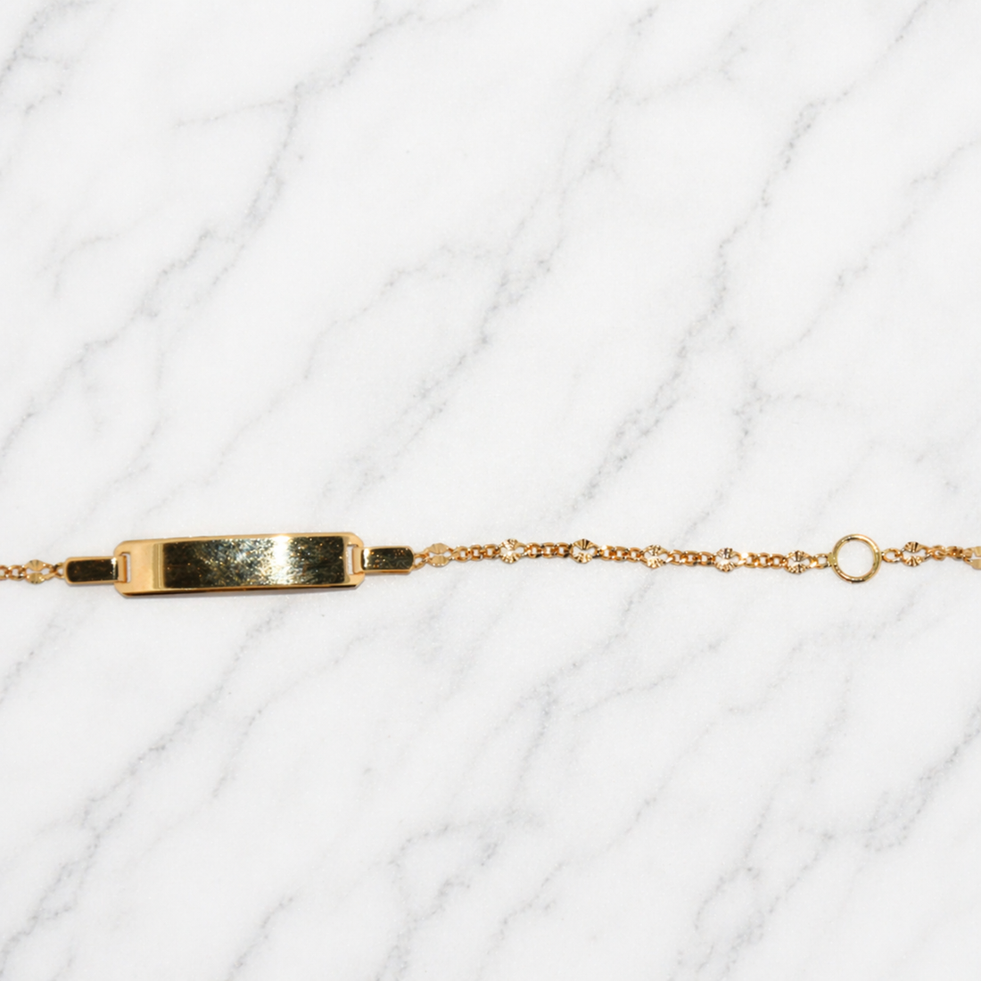 19.2K Portuguese Kids Gold Starburst adjustable link bracelet with a rectangular tag on a white textured background 