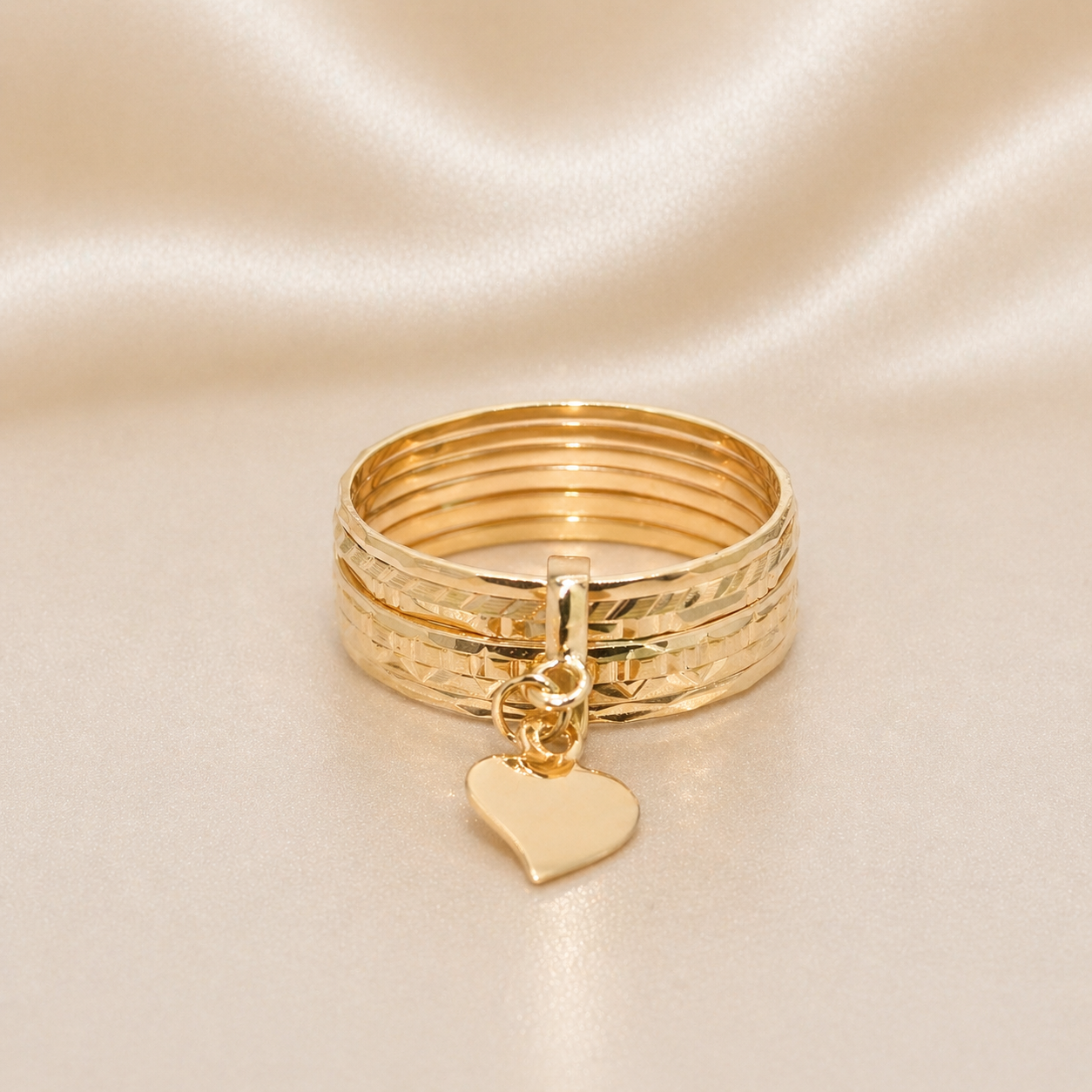 Stack of gold rings with a heart charm. 7 band Portuguese gold ring 