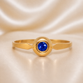 Gold ring with a blue gemstone on a beige fabric background 19.2K Portuguese Gold | Blue Stone Circle RingBaby Infant Ring 