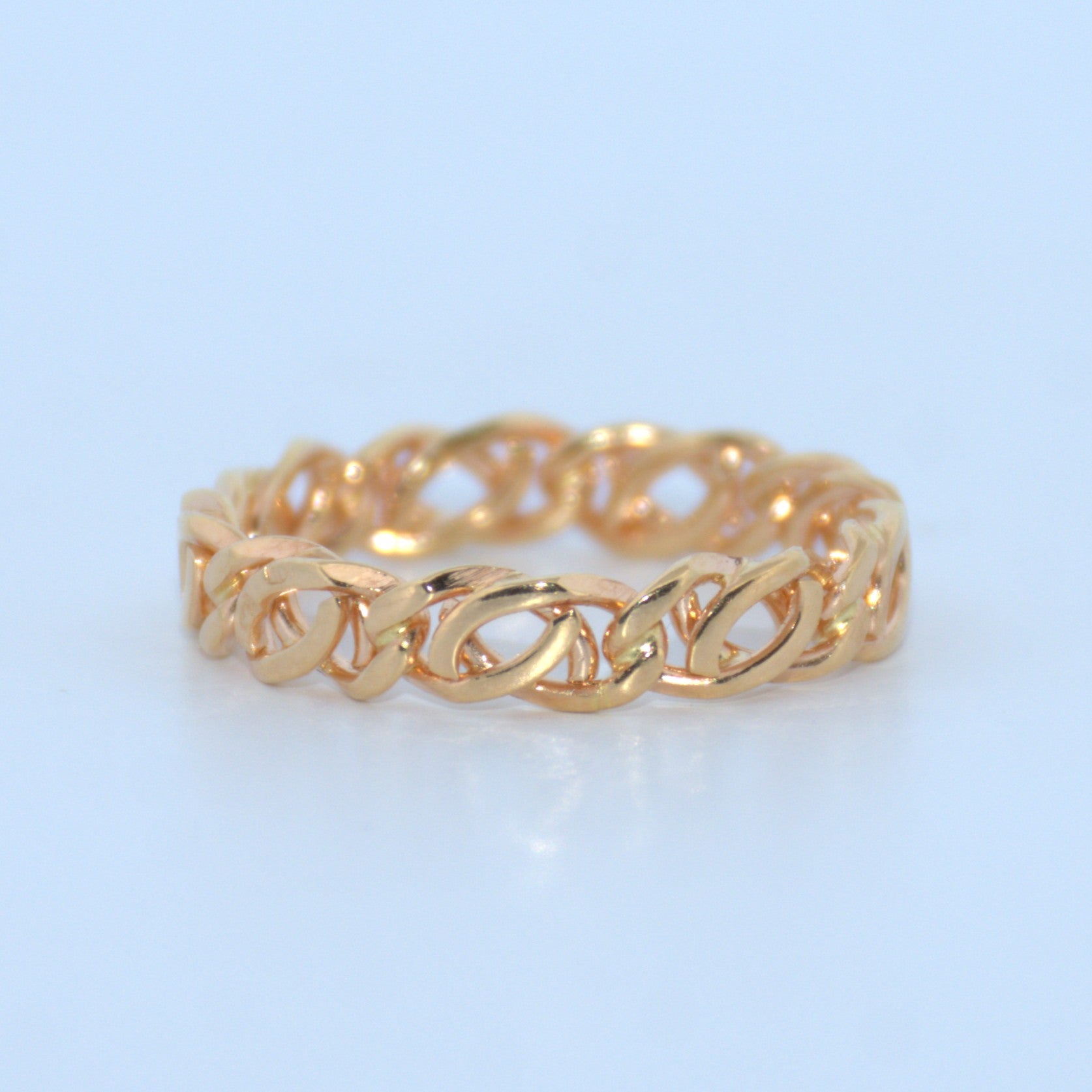 Gold chain-style ring on a light blue background