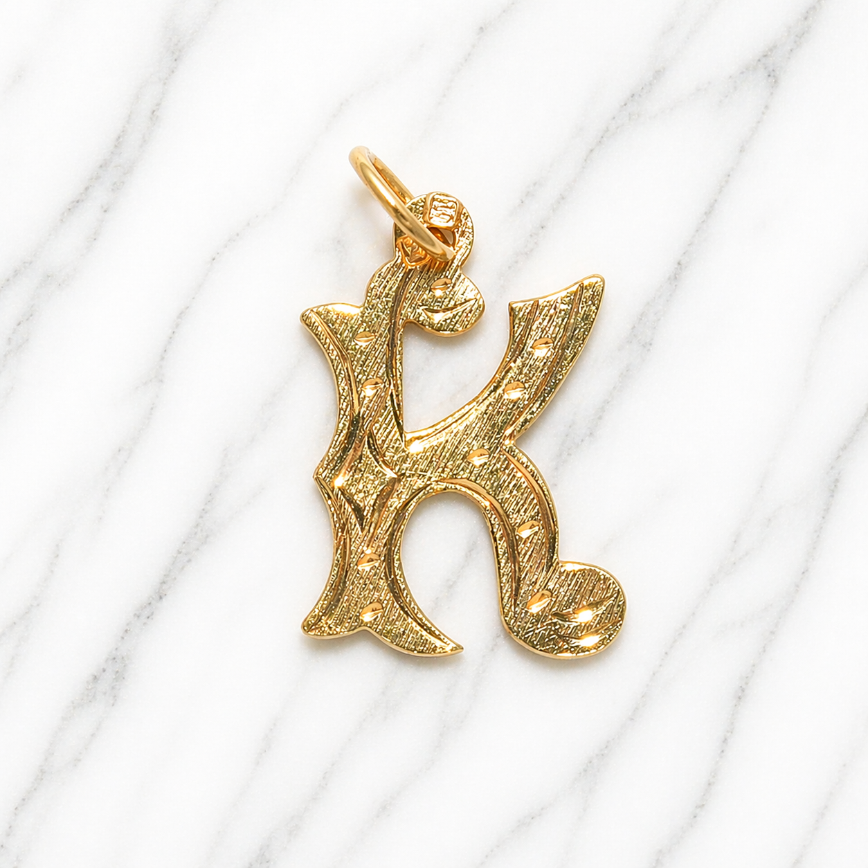 Gold letter 'K' pendant on a white marble background 19.2K Portuguese Gold | Large Initial Charm Letter Pendants Letter K Name 