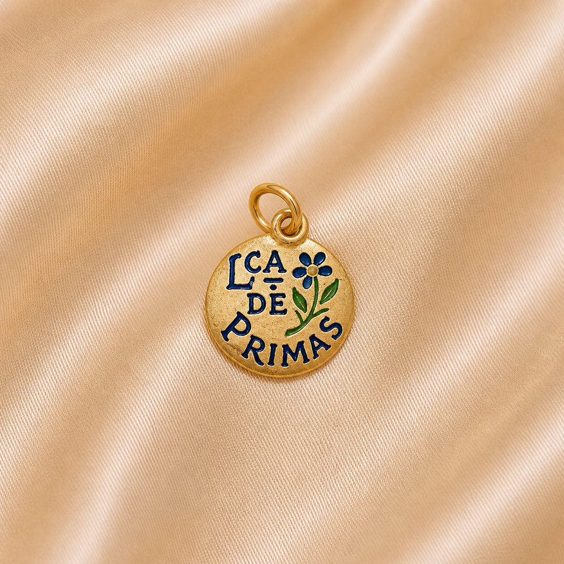 Gold charm with 'LCA DE PRIMAS' text on a beige fabric background 19.2K Portuguese Gold | Lca De Primas ( Cousins ) Charms