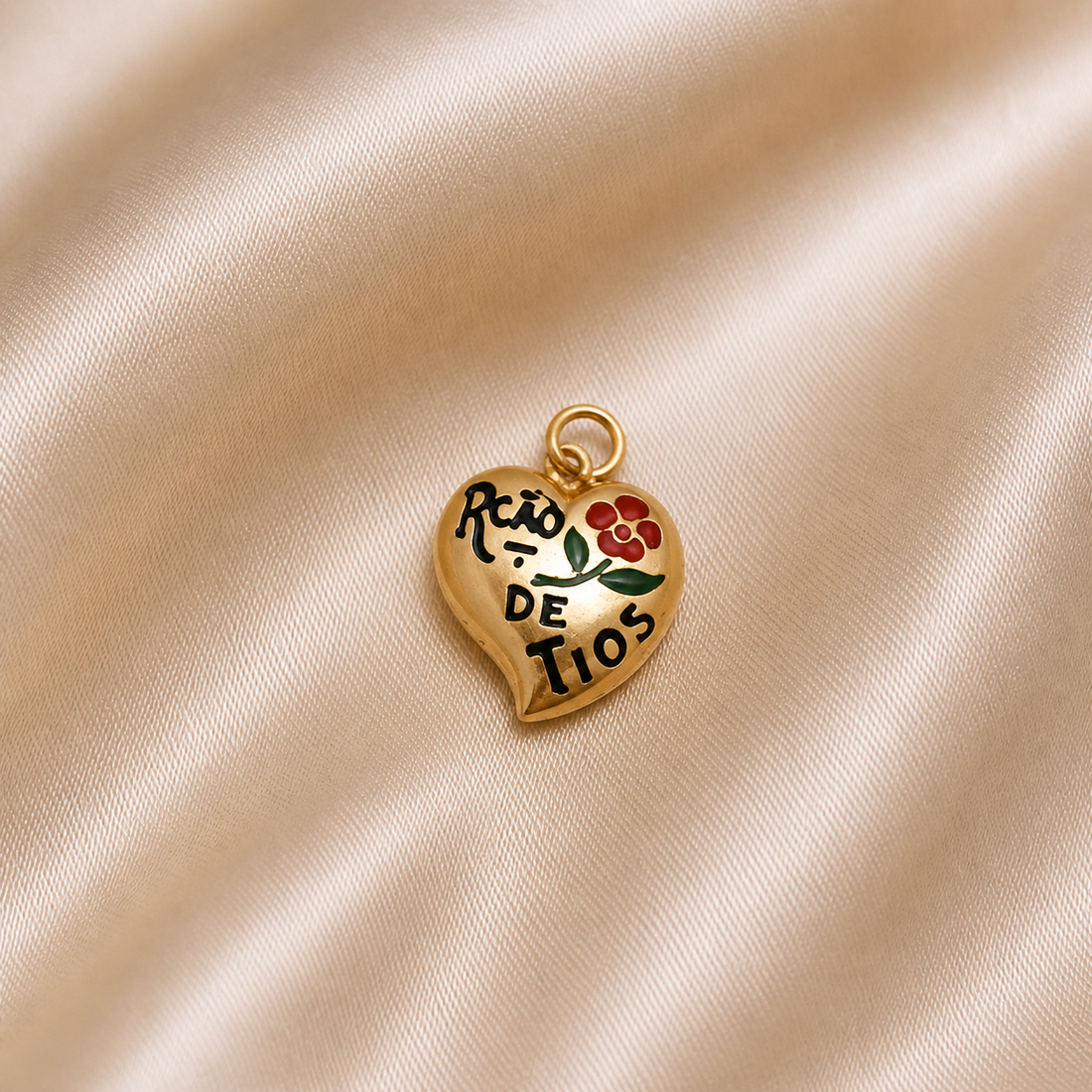 Heart-shaped gold charm with floral design and text on a beige fabric background 19.2K Portuguese Gold | Lca De Tios Heart Charm