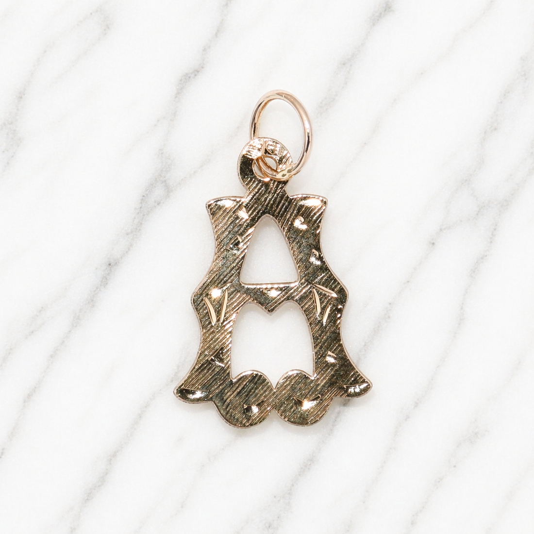 Gold pendant with intricate design on a white marble surface 19.2K Portuguese Gold | Medium Initial Charms Letter A Initial