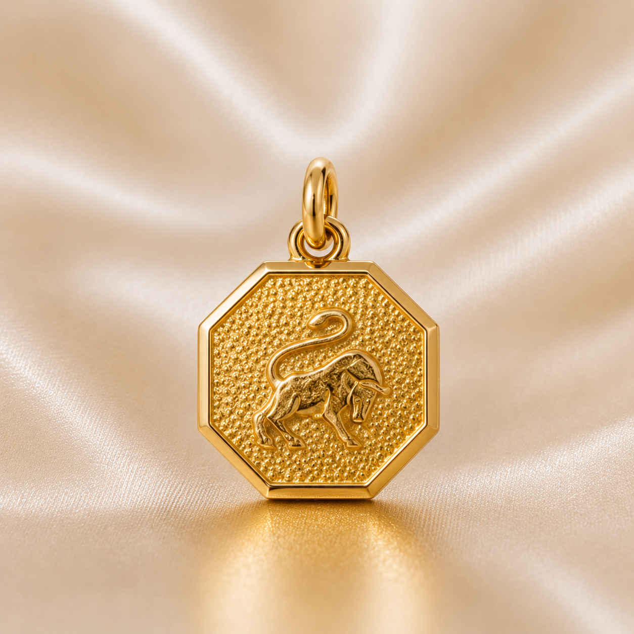 Gold hexagonal pendant with a lion emblem on a beige satin background 19.2K Portuguese Gold | Octagon Zodiac Charms Taurus Charm