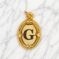 Gold pendant with letter 'G' on a marble background 19.2K Portuguese Gold | Oval Initial Charms