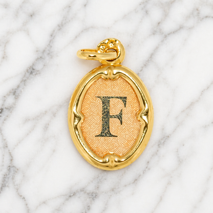 Gold pendant with letter 'F' on a marble background 19.2K Portuguese Gold | Oval Initial Charms