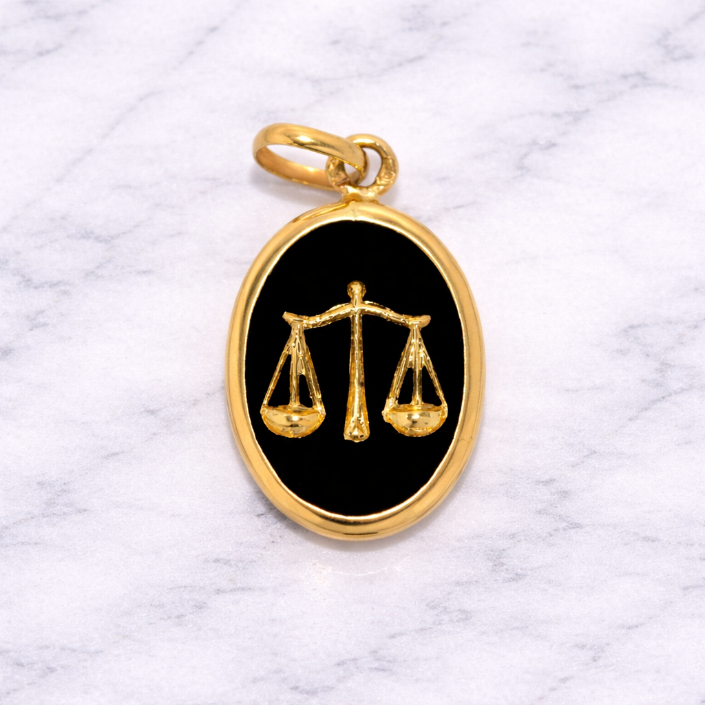 19.2K Portuguese Gold pendant with Libra zodiac symbol on a black background, placed on a marble surface.